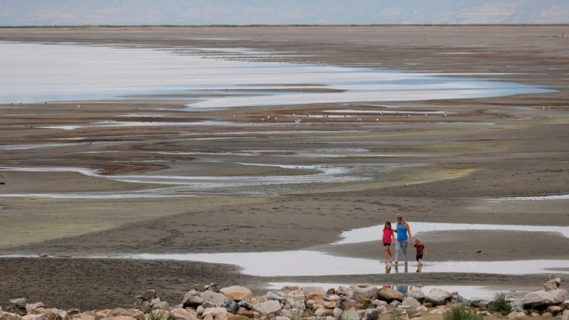 Three people stand in front of the expansive Salt Lake flats, with dried out puddles throughout the landscape